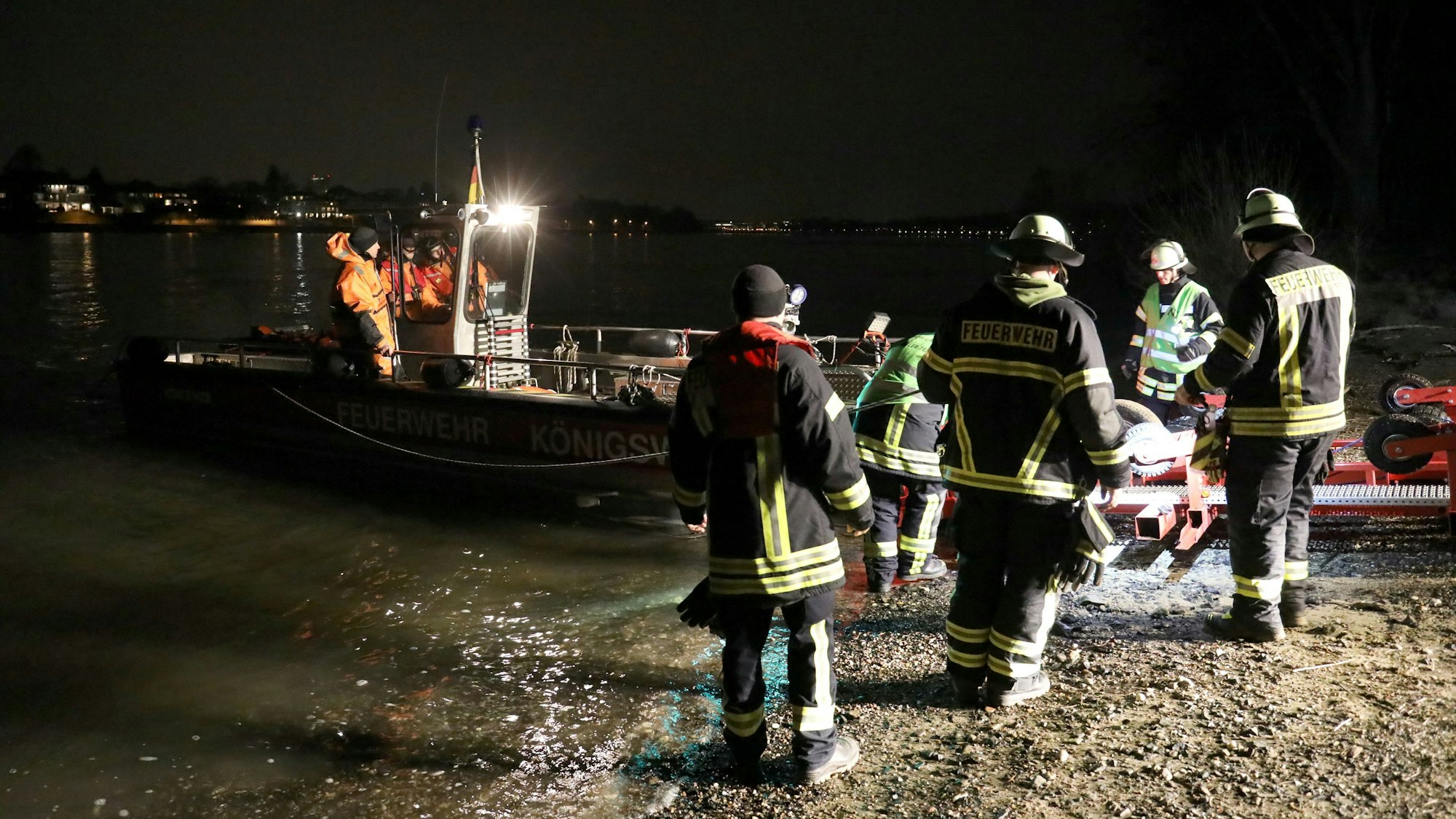 Feuerwehrleute helfen nachts bei der Rettung einer Frau aus dem Rhein in Bonn.