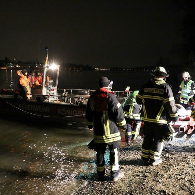 Feuerwehrleute helfen nachts bei der Rettung einer Frau aus dem Rhein in Bonn.
