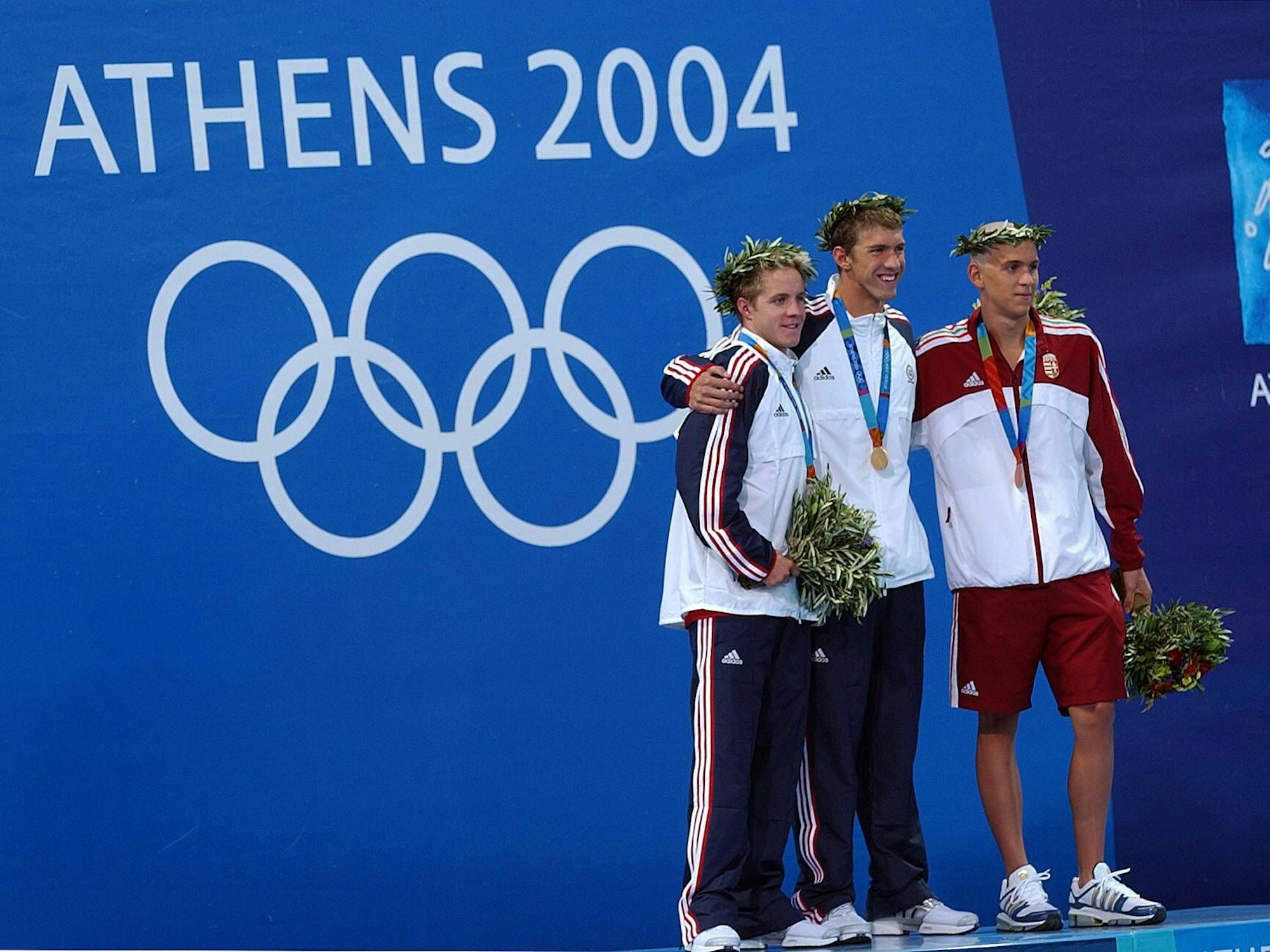 Erik Vendt, Michael Phelps und Laszlo Cseh lächeln bei der Siegerehrung bei den Olympischen Spielen 2004 in die Kameras.