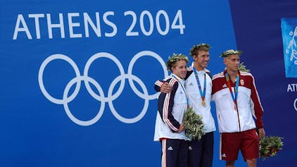 Erik Vendt, Michael Phelps und Laszlo Cseh lächeln bei der Siegerehrung bei den Olympischen Spielen 2004 in die Kameras.