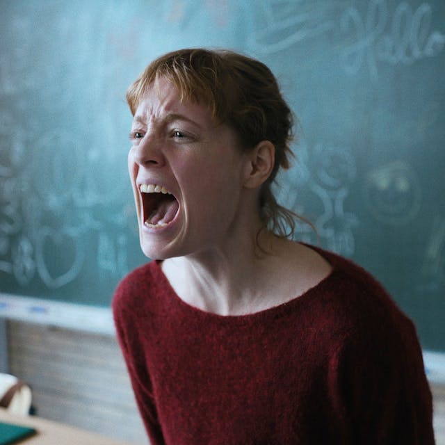 Eine junge Lehrerin steht schreiend vor der Schultafel.&nbsp;