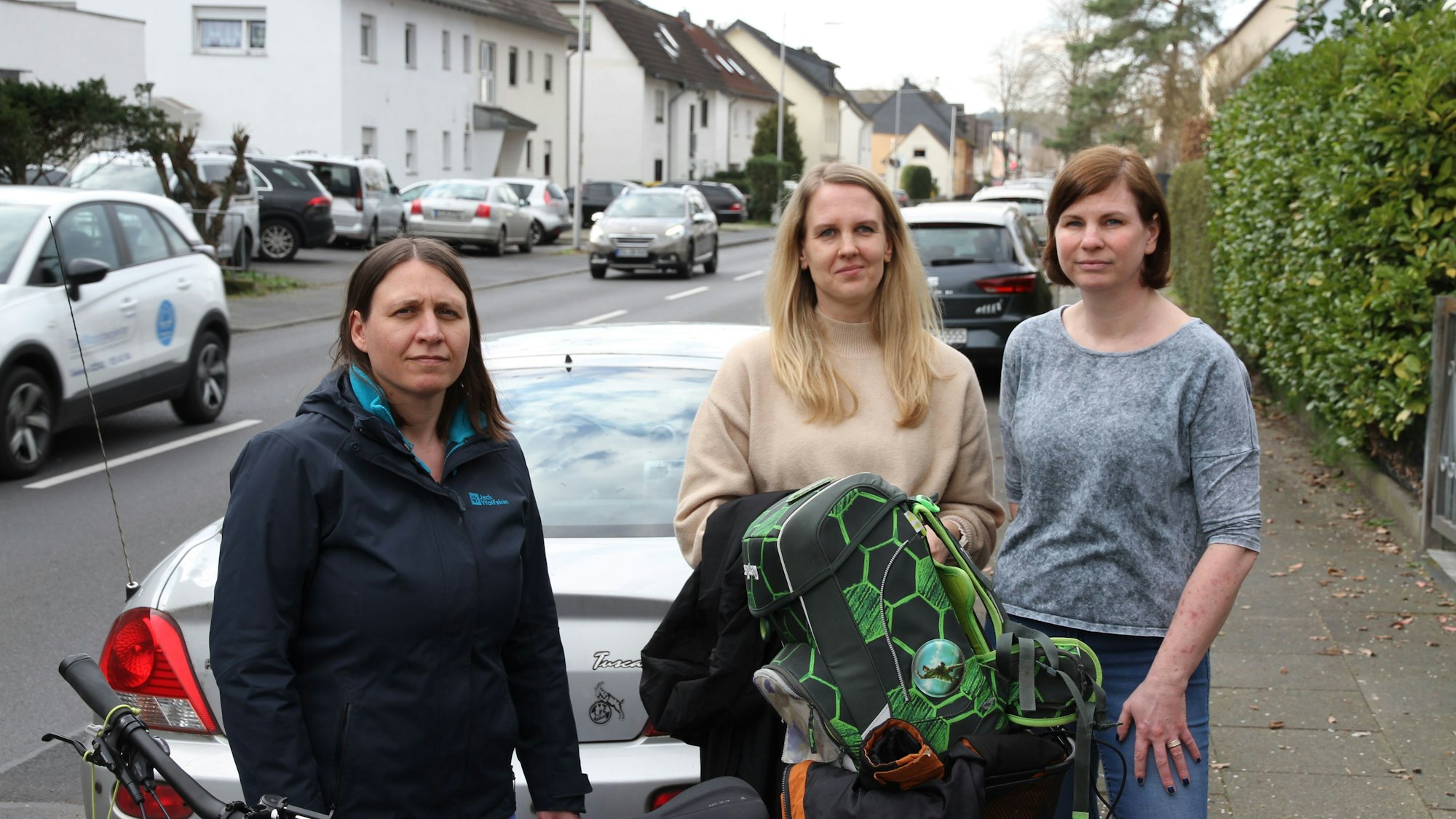 Drei Frauen hinter einem Fahrrad mit einem Schulranzen