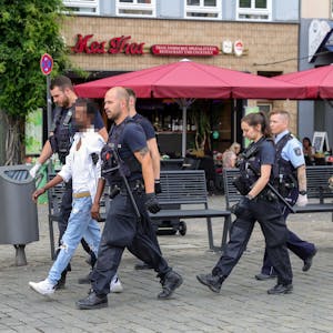 Polizisten führen einen mutmaßlichen Handydieb auf dem Kölner Heumarkt ab.