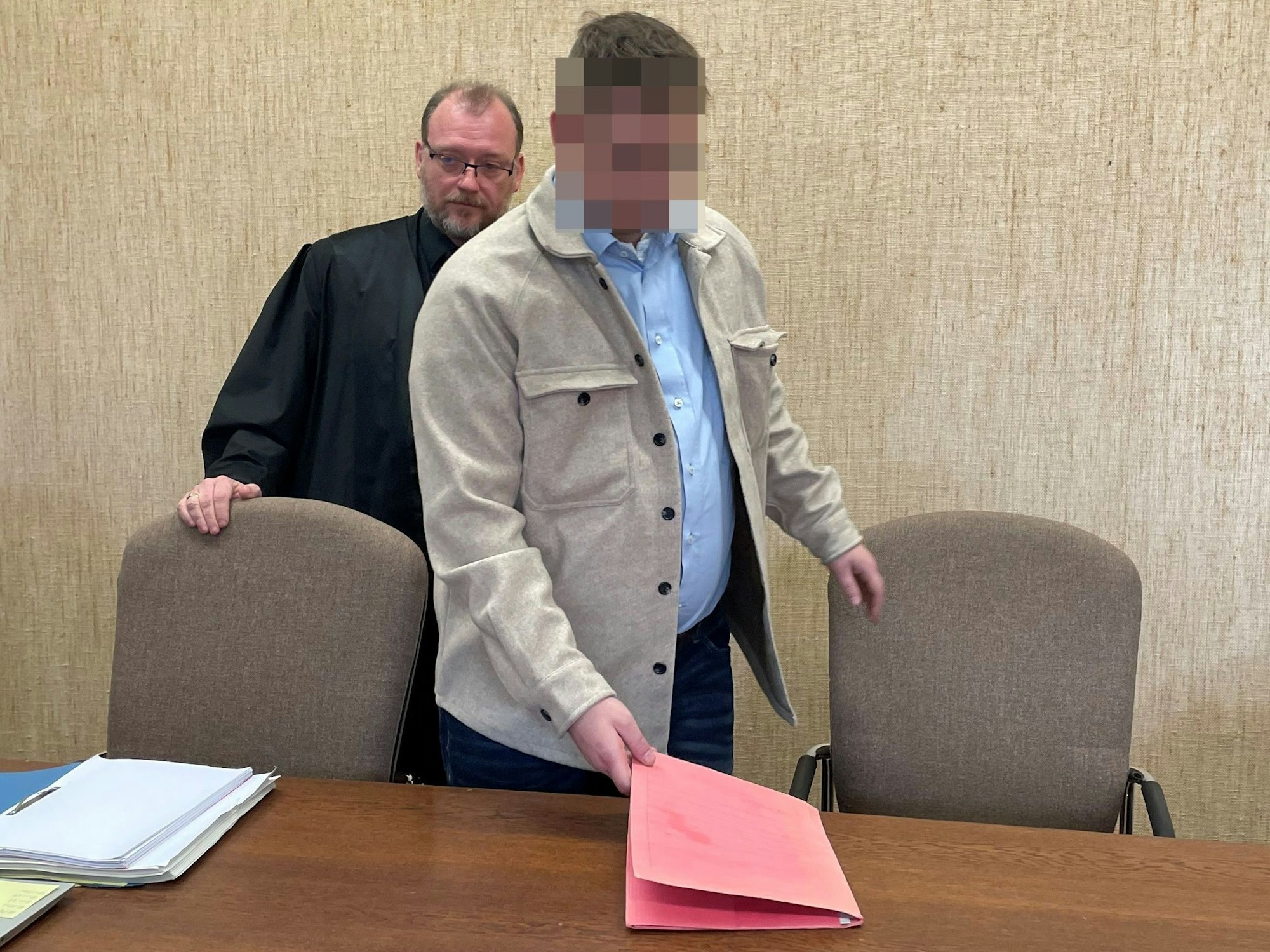 Der Beschuldigte legt eine Mappe auf die Anklagebank, hinter ihm steht sein Anwalt.