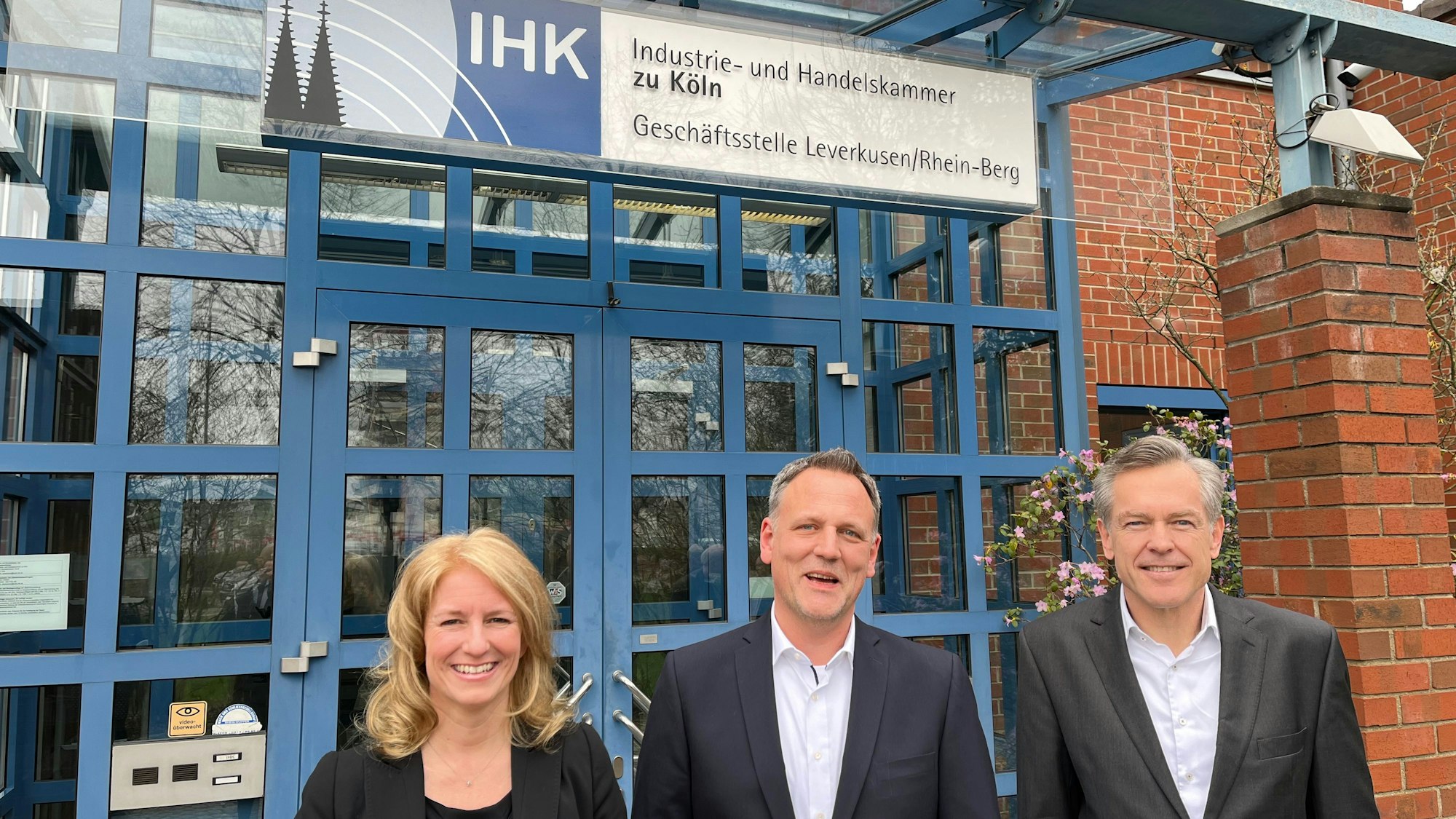 IHK-Präsidentin Nicole Grünewald und Hauptgeschäftsführer Uwe Vetterlein umrahmen Jörg Hausmann, den neuen Leiter der Zweigstelle in Opladen, vor der sie stehen.
