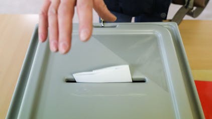 Eine Frau wirft ihren Stimmzettel für die Oberbürgermeisterwahl in die Wahlurne.