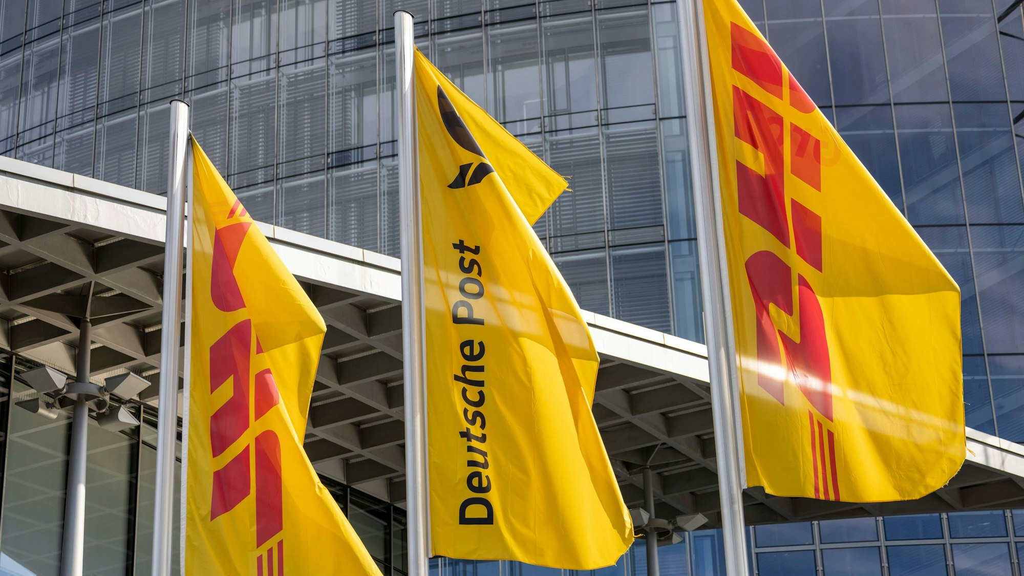 Flaggen der Deutschen Post und der DHL Group wehen vor der Zentrale der Deutschen Post.