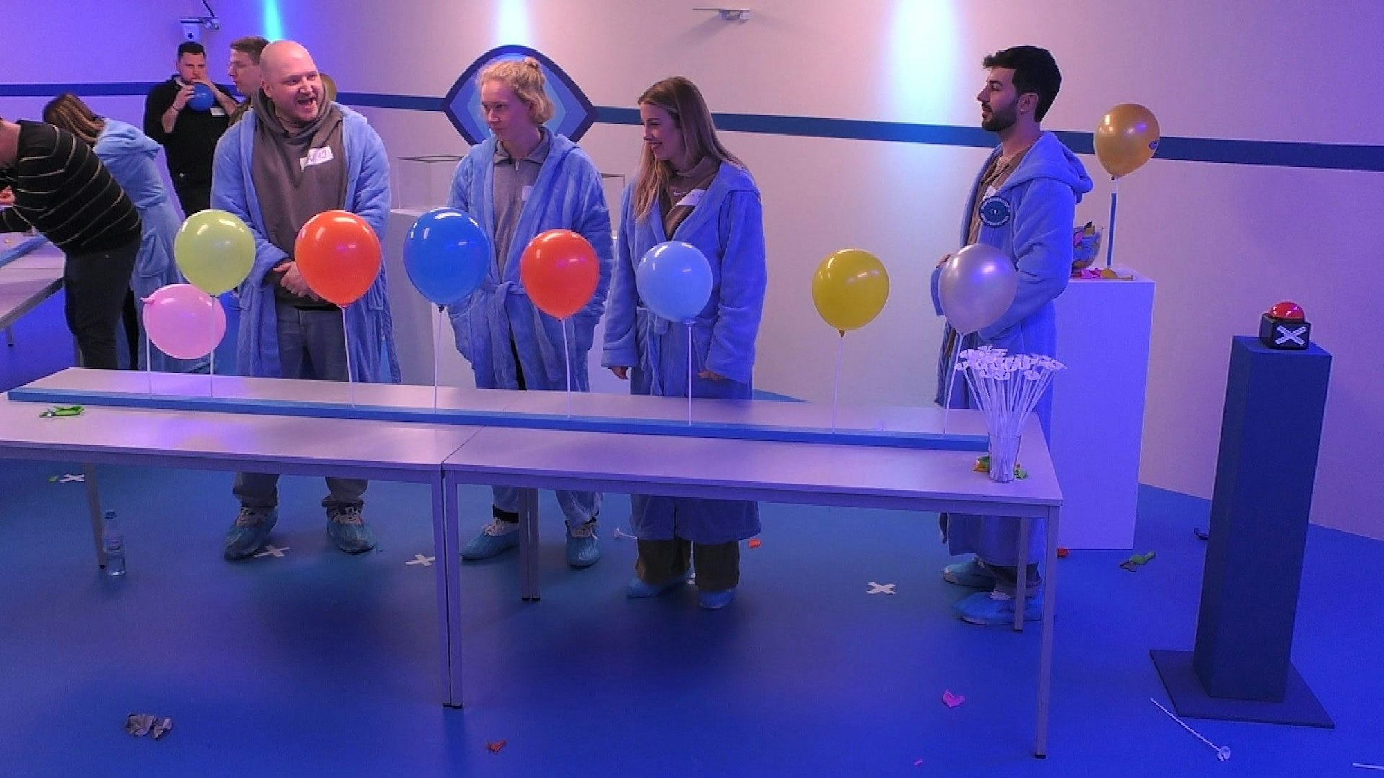 Max Richard Leßmann, Jonas Lennefer, Lina Westphal und Sani Jakimovski stehen vor einer Reihe von Luftballons beim Spiel im „Big Brother“ Container