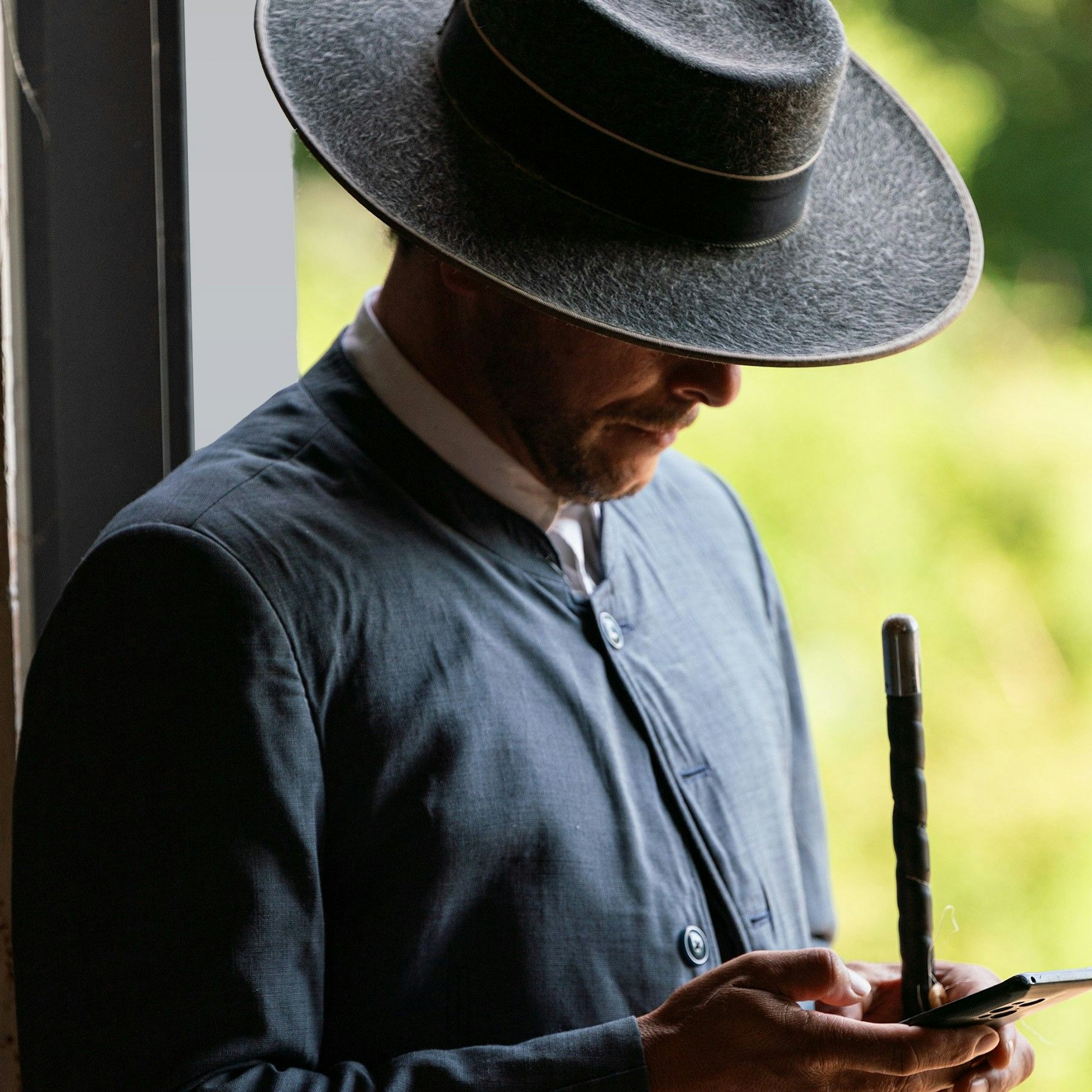 Ein Mann in der traditionellen Kleidung eines Bereiters schaut im Rahmen einer Pferdeschau in Spanien auf sein Smartphone.