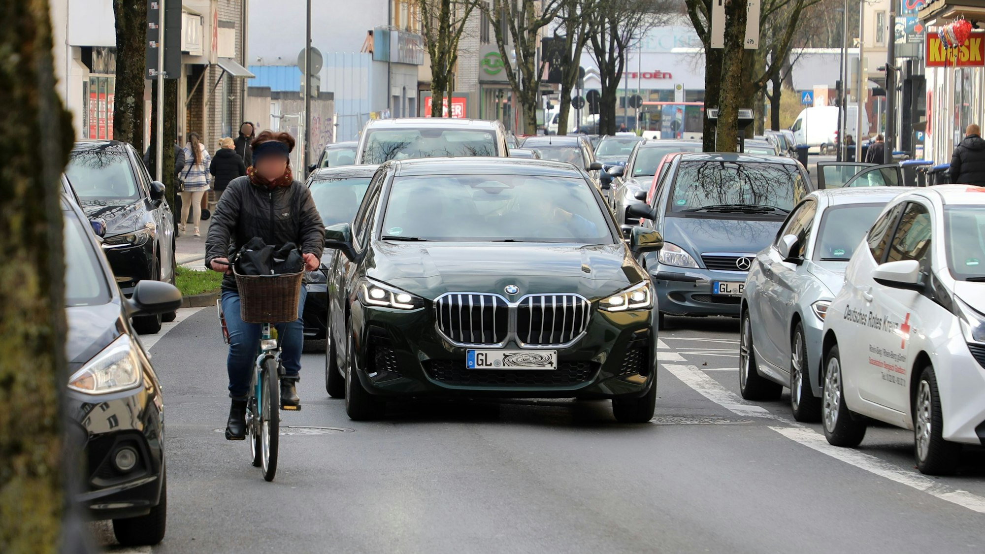 Eine Radfahrerin fährt auf der unteren Hauptstraße in Bergisch Gladbach, dahinter fährt ein Auto.