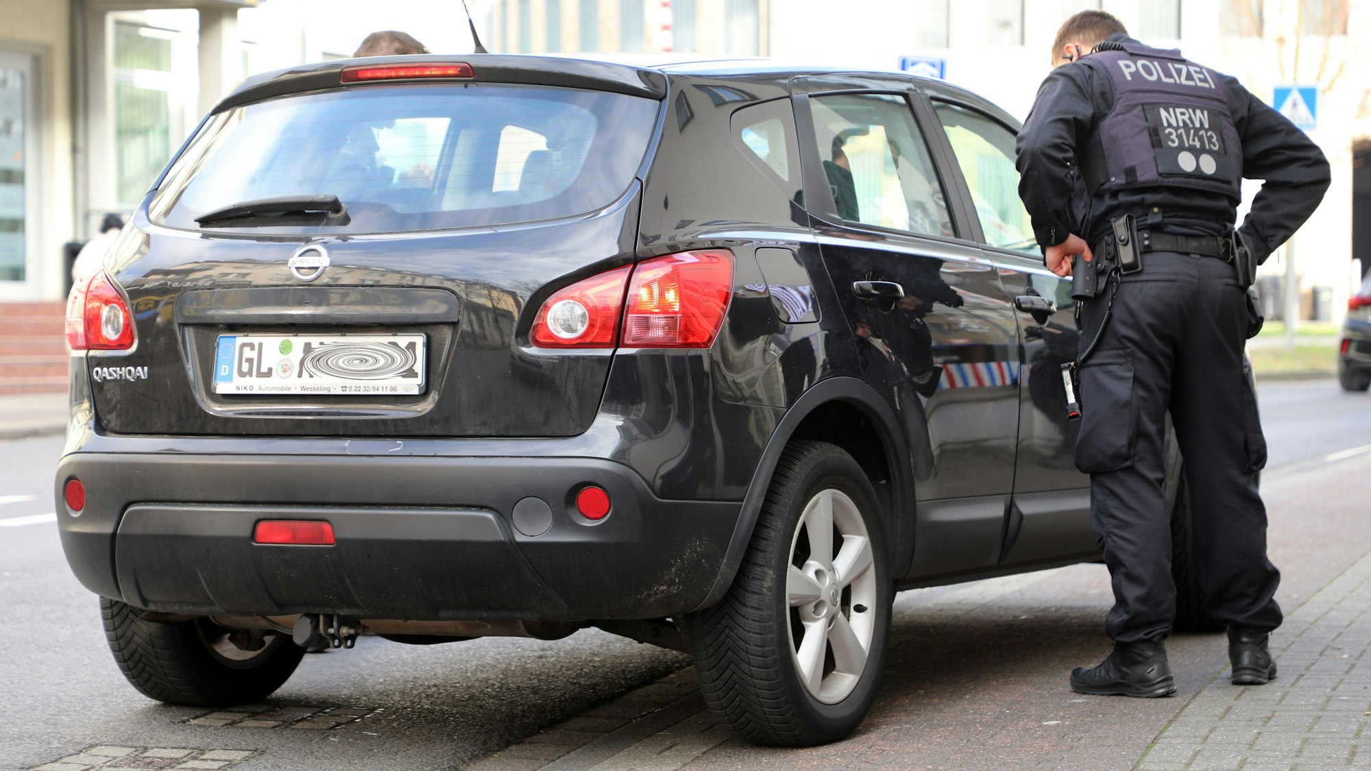 Zwei Polizeibeamte kontrollieren einen Autofahrer.