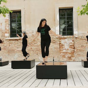 Vier Frauen tanzen in Stöckelschuhen auf Podesten.