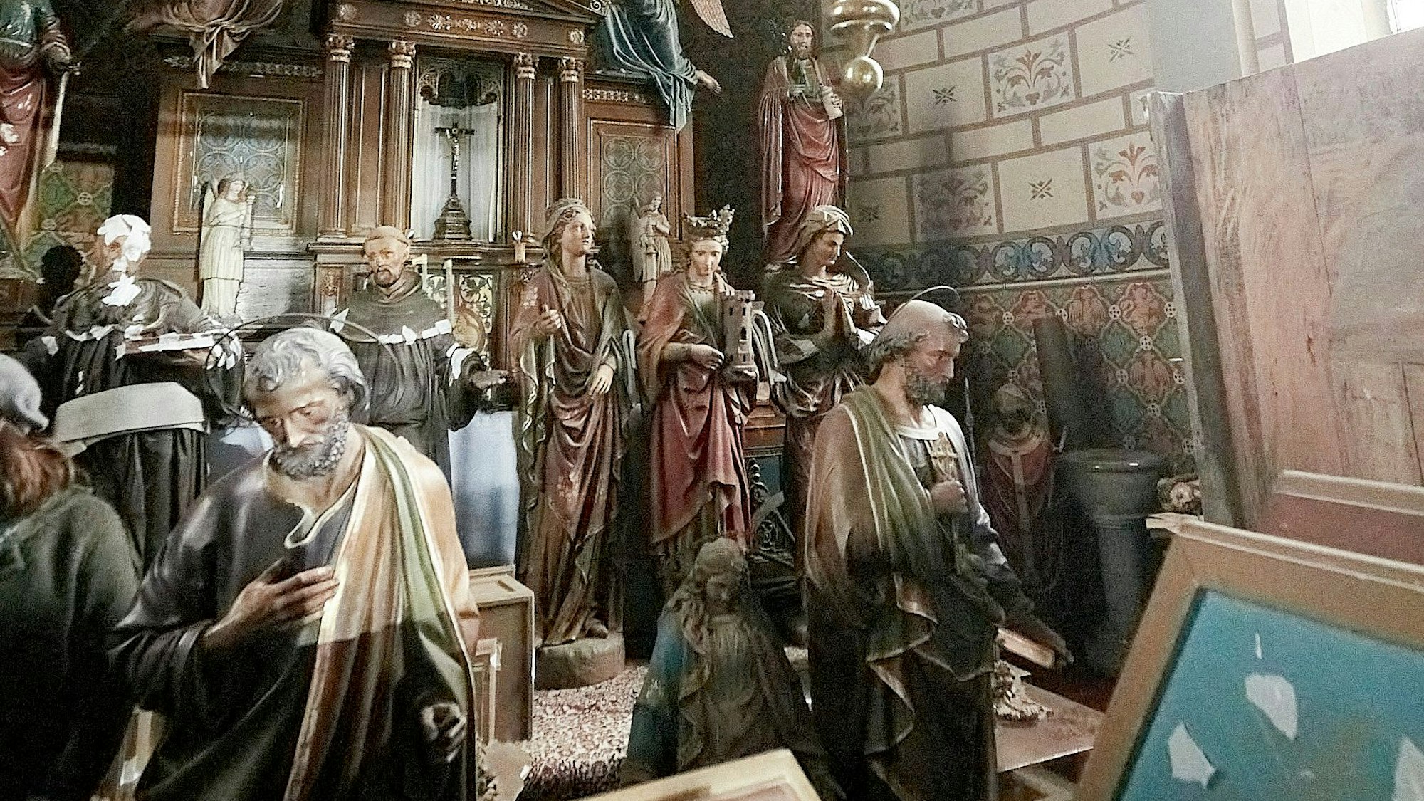 Zahlreiche Kirchenfiguren stehen zusammengerückt in einem Altarraum.