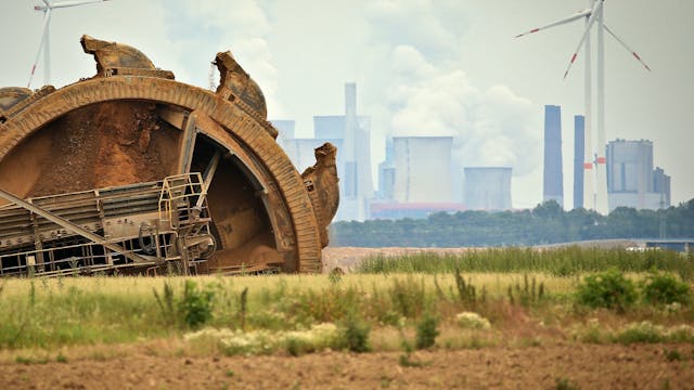 Ein Braunkohlebagger baggert im Tagebau Garzweiler, im Hintergrund steht ein Kraftwerk hinter Windrädern. (Archivbild)