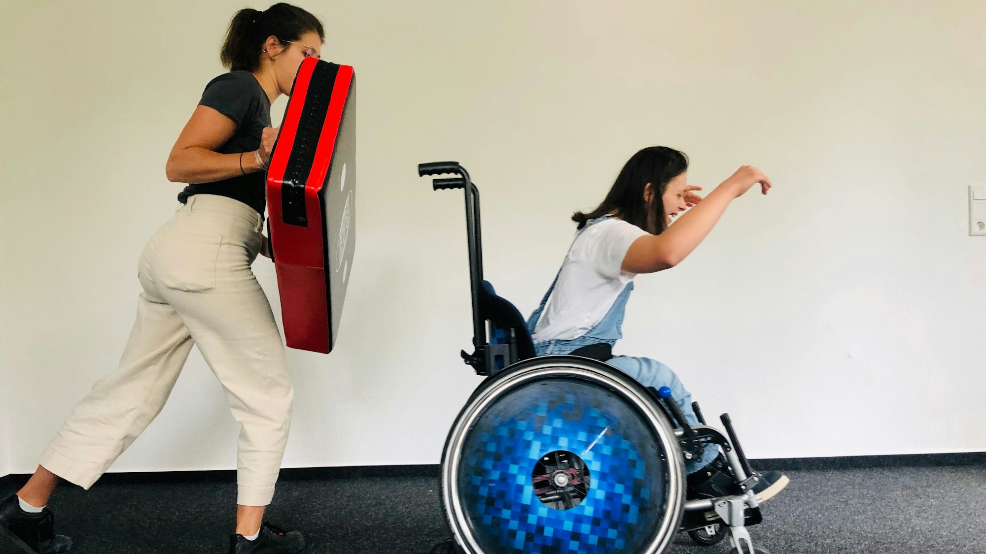 Jana Busch und Anna Schuck üben eine Rollstuhl-Abwerhtechnik.