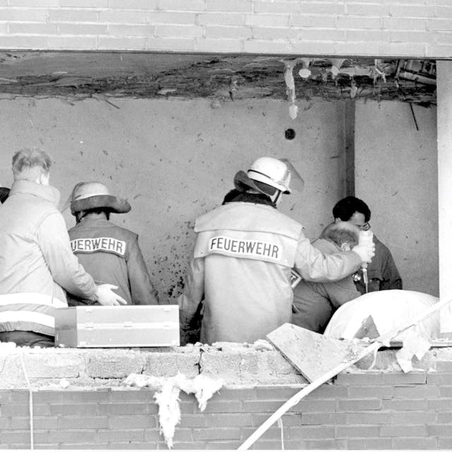 Das Bild zeigt Einsatzkräfte, de sich kurz nach dem Amoklauf um einen Verletzten im Gerichtssaal kümmern. In der Fassade klafft ein großes Loch.