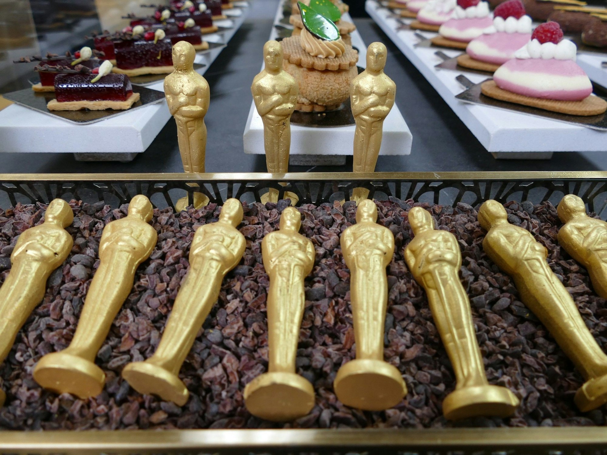 Mit Gold besprühte Oscar-Schoko-Figuren liegen in einem Beet aus Kakaobohnenschalen