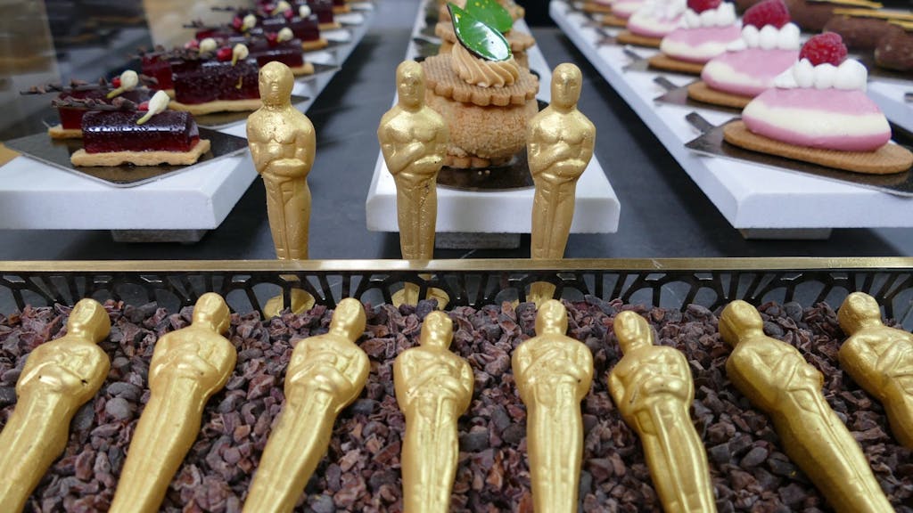 Mit Gold besprühte Oscar-Schoko-Figuren liegen in einem Beet aus Kakaobohnenschalen