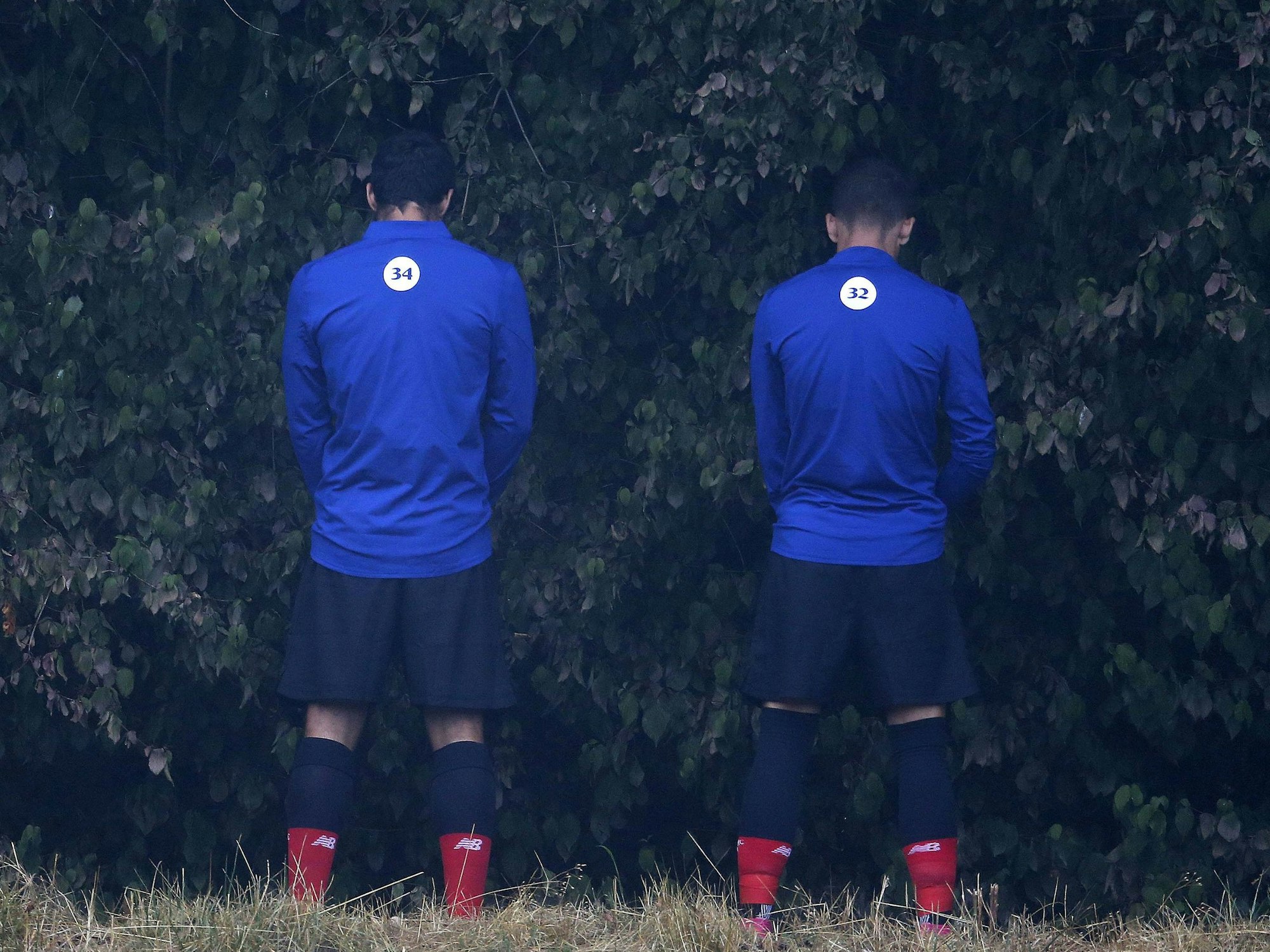 Zwei Auswechselspieler von Atletico Bilbao verrichten ihre Notdurft im Gebüsch.