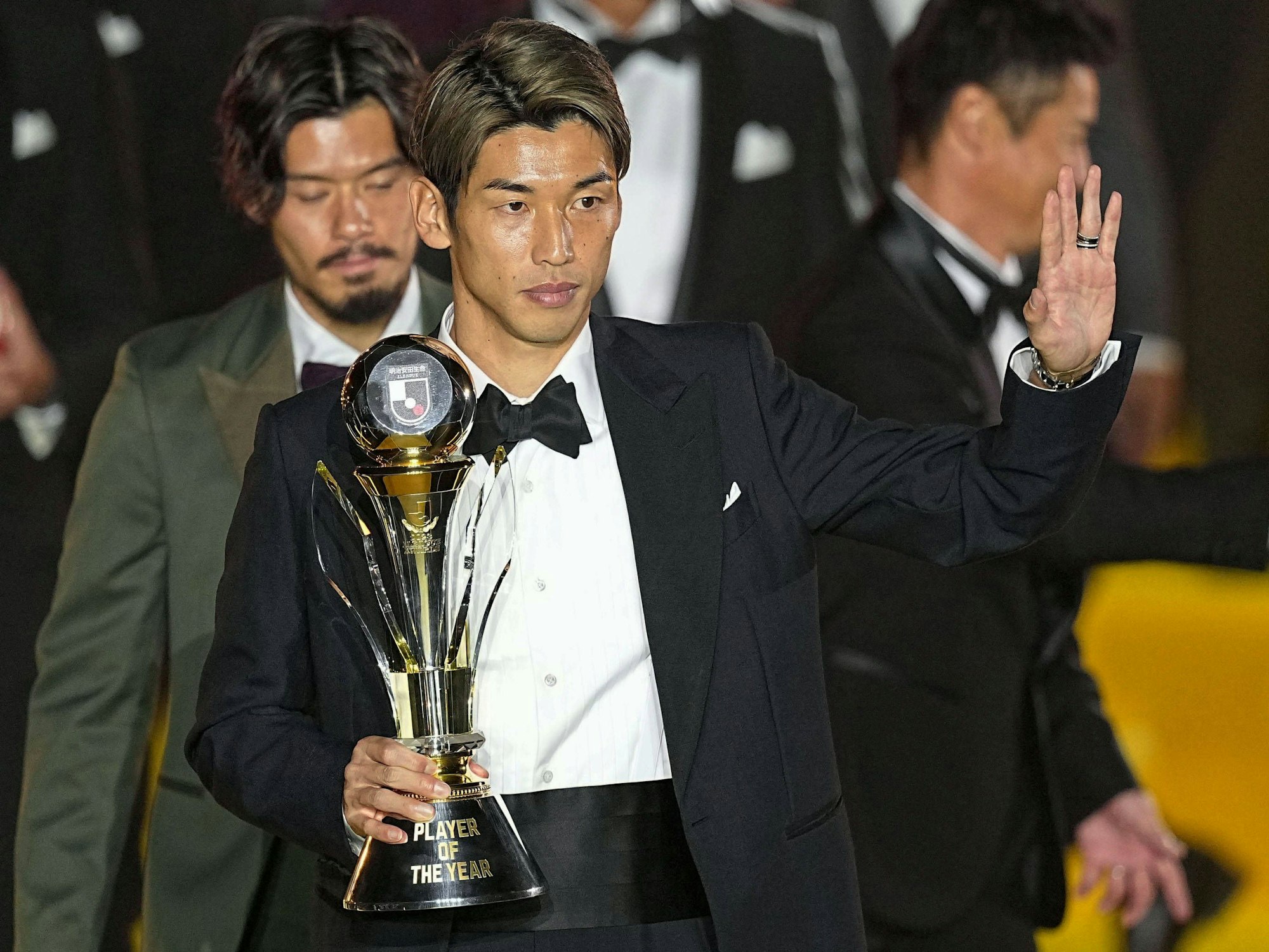 Yuya Osako grüßt im Smoking mit der Trophäe für den Spieler des Jahres im Arm.