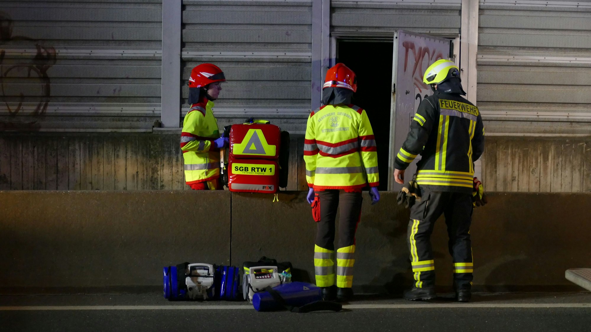 Rettungskräfte stehen an der Uferstraße in Troisdorf an einer Tür im Lärmschutzzaun.