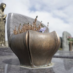 Eine Metallschale mit Blumen auf einem Grab.