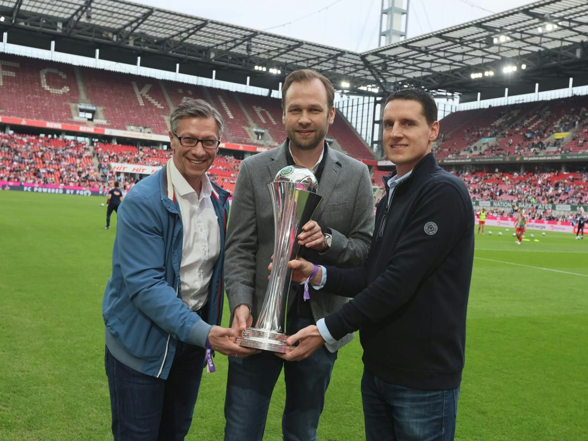 Von links: Dr. Christos Katzidis (FVM), Robert Voigtsberger von der Stadt Köln und Manuel Hartmann vom DFB bei der Übergabe des DFB-Pokals an die Stadt.