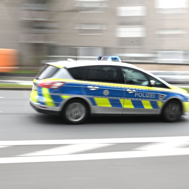 Zu sehen ist ein Polizeiwagen in der Seitenansicht, der durch die Kölner Innenstadt rast.