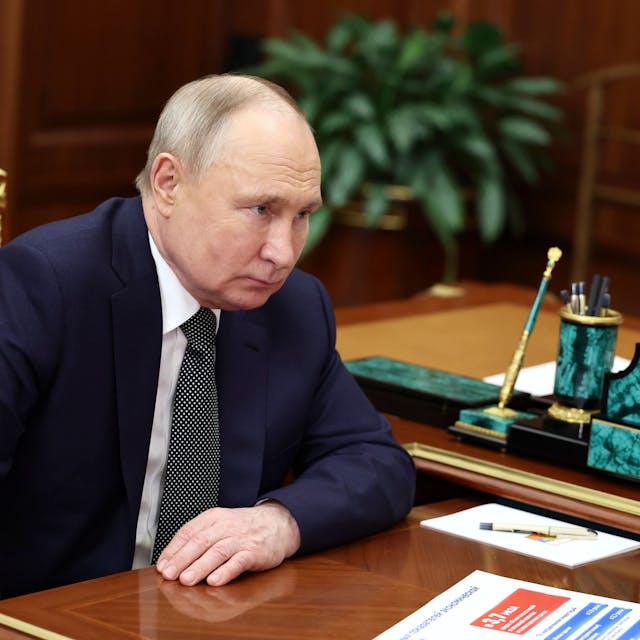 Russlands Präsident Wladimir Putin sitzt in seinem Büro im Moskauer Kreml und hört bei einem Gespräch zu. Er trägt einen blauen Anzug und Krawatte.