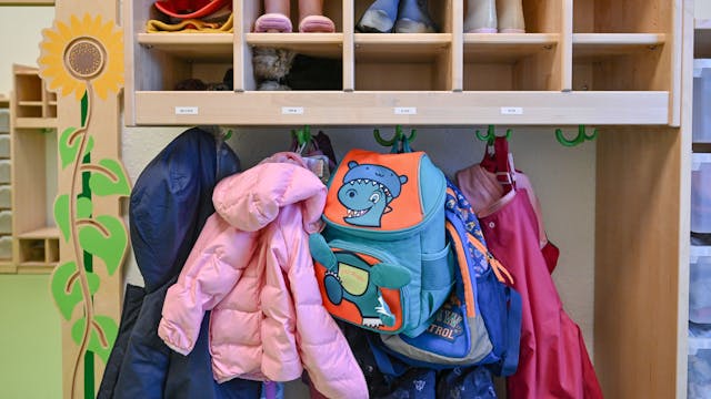 Kleidung von Kindern hängt in einem Kindergarten.