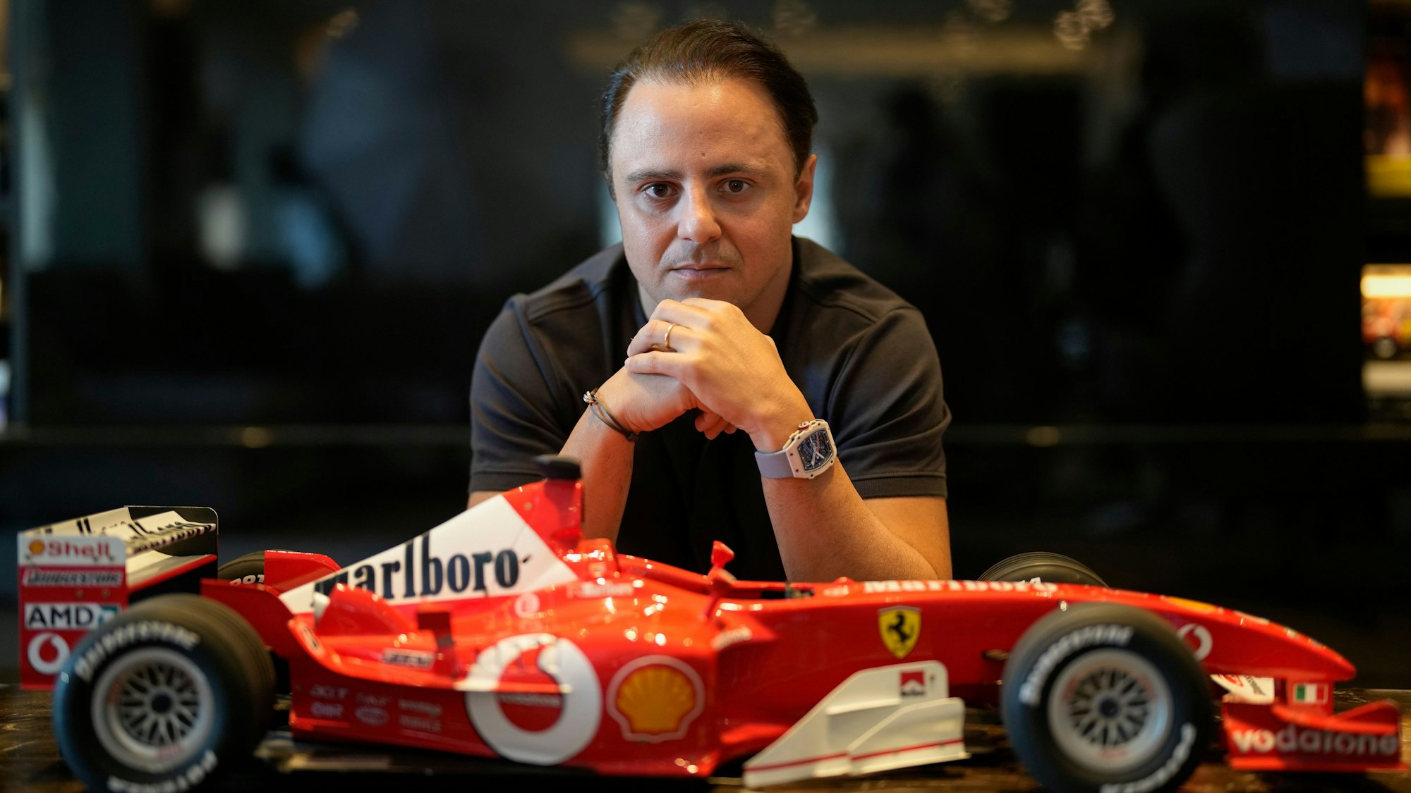 Felipe Massa sitzt vor einem kleinen Modell-Ferrari.