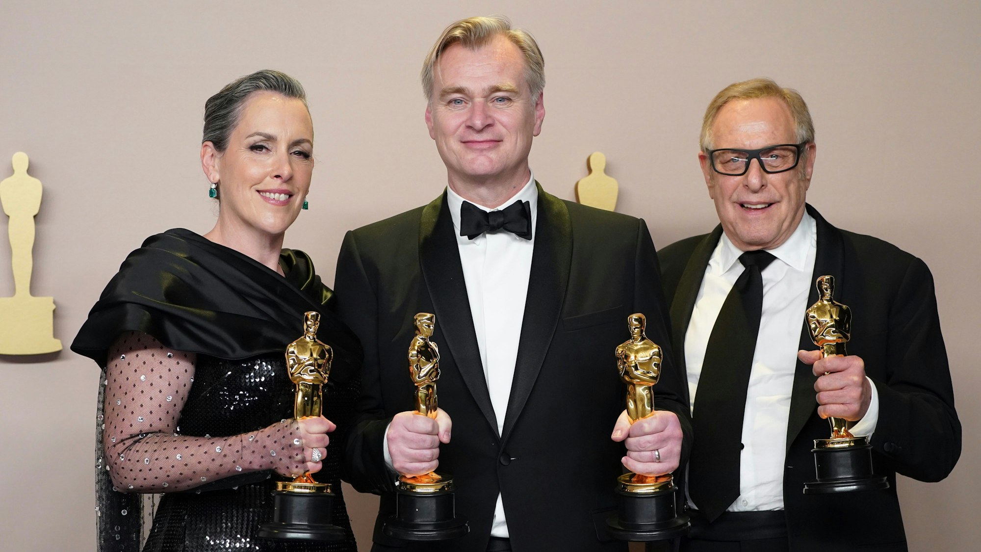 (V.l.) Emma Thomas, Christopher Nolan und Charles Roven posieren mit ihren frischen Oscar-Statuen für ihren Film „Oppenheimer“.