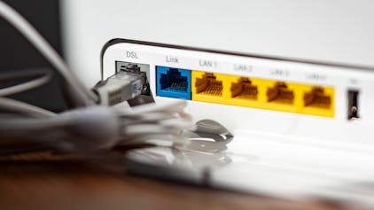 Ein LAN-Kabel steckt im DSL-Steckplatz eines WLAN-Routers. Die Bundesnetzagentur hat erstmals in Deutschland das „Recht auf schnelles Internet“ durchgesetzt. (Symbolbild)