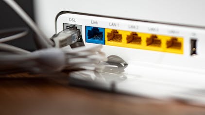 Ein LAN-Kabel steckt im DSL-Steckplatz eines WLAN-Routers. Die Bundesnetzagentur hat erstmals in Deutschland das „Recht auf schnelles Internet“ durchgesetzt. (Symbolbild)