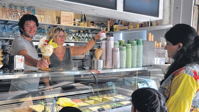 Seit Jahrzehnten versorgen Lorenzo Cucco und Nicoletta Bez Elsdorf mit Speiseeis. Hier stehen sie hinter der Eistheke, eine Frau mit Kindern wird bedient.