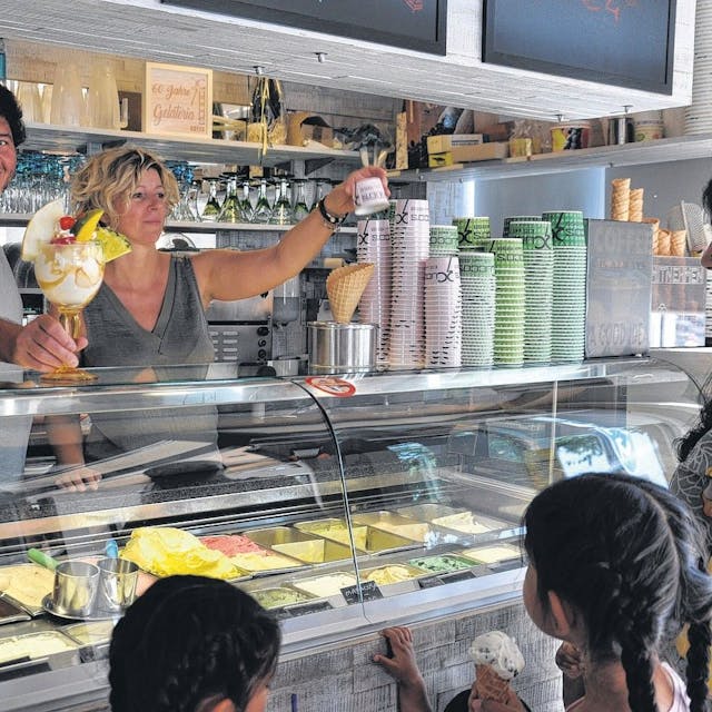 Seit Jahrzehnten versorgen Lorenzo Cucco und Nicoletta Bez Elsdorf mit Speiseeis. Hier stehen sie hinter der Eistheke, eine Frau mit Kindern wird bedient.