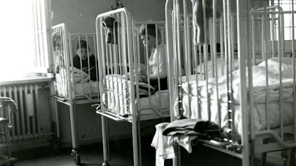 Heimkinder in Gitterbetten im Landeskrankenhaus Bonn des LVR. Das Aufnahmedatum der Schwarzweißfotografie liegt zwischen 1950 und 1970.