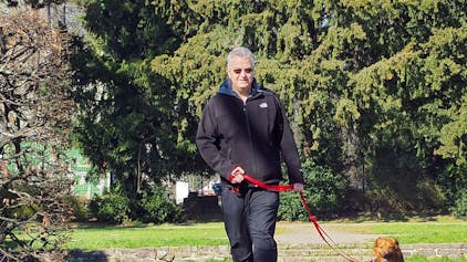 Ein Mann geht mit seinem Hund in einem Park spazieren.