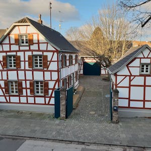 Zwei historische Fachwerkbauten einer Hofanlage mit großer Linde im Innenhof.