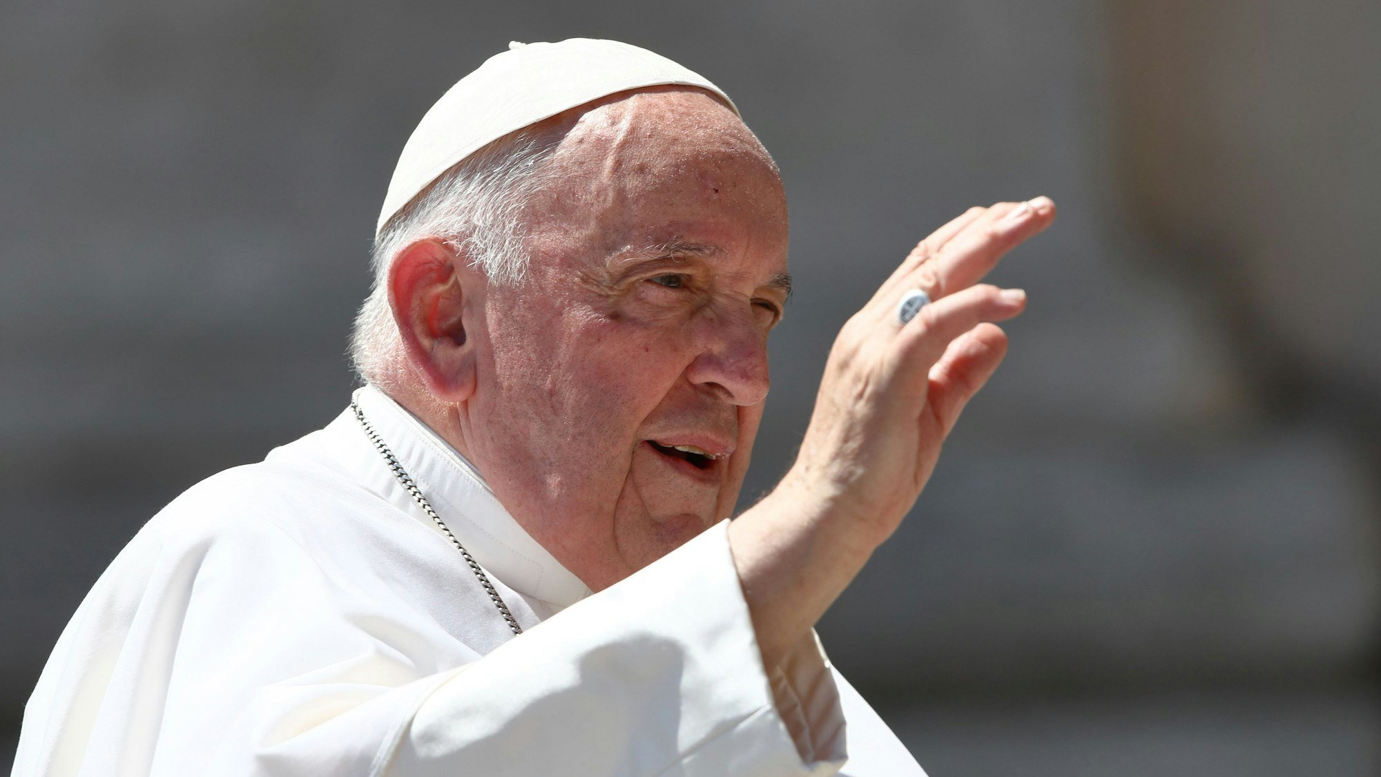 Papst Franziskus hat während seiner wöchentlichen Generalaudienz auf dem Petersplatz die rechte Hand zum Segen erhoben. Er trägt eine weiße Soutane und eine weiße Kappe, genannt Pileolus.