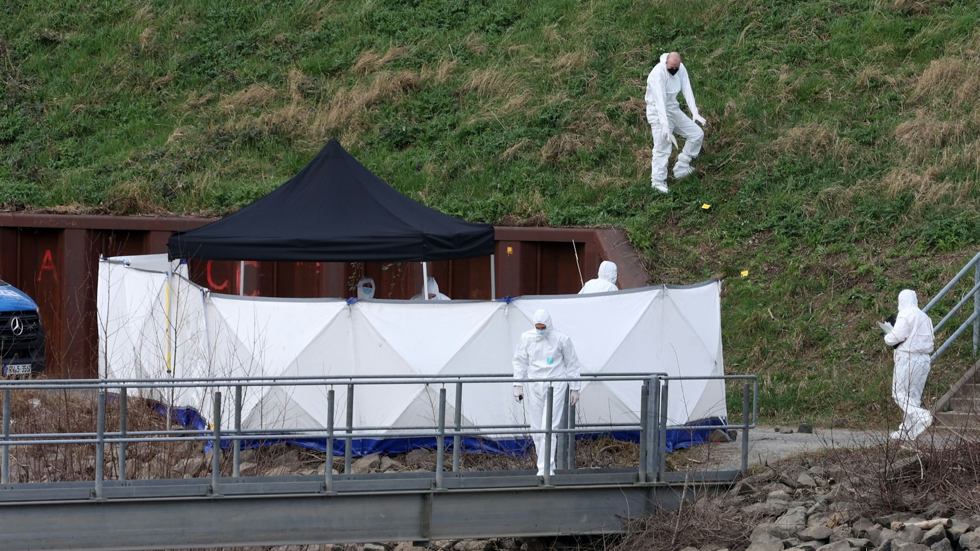 Spurensicherer der Polizei untersuchen eine Böschung am Tatort im Mülheimer Hafen.