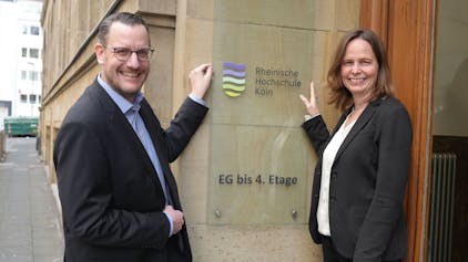 Martin Topp, Geschäftsführer und Kanzler, und Präsidentin Claudia Bornemeyer zeigen auf das neue Logo der umbenannten Rheinischen Hochschule