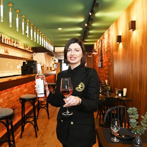 Ana Gogichashvili steht mit einer Flasche Wein in ihrem Restaurant.