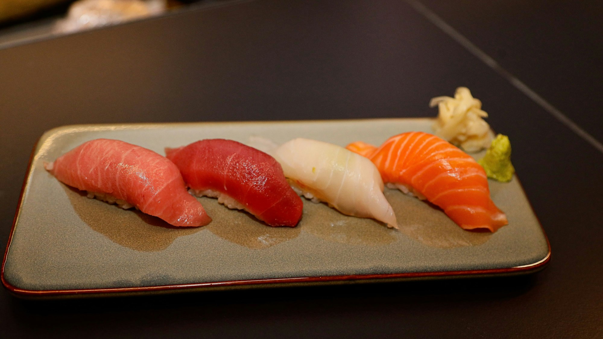 Sushi mit Ouro, Akami, Zander und Lachs auf einem länglichen Teller.