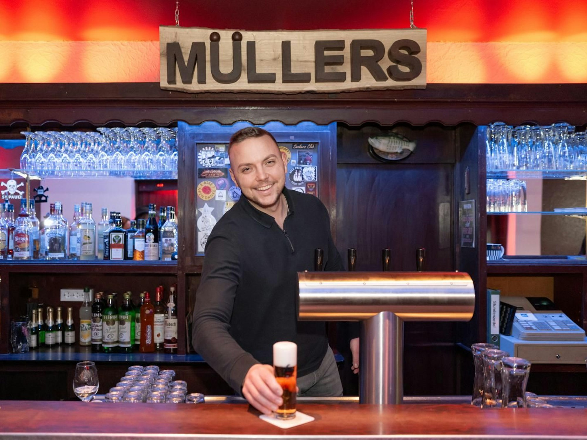 Ein Kellner stellt in der Kneipe „Müllers“ in Köln Ehrenfeld ein Bier auf die Theke.