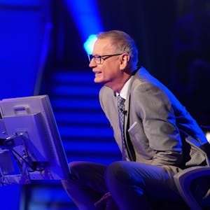 „Wer wird Millionär?“-Moderator Günther Jauch sitzt am Pult der RTL-Quizshow und blickt lächelnd zu einem Kandidaten herüber.