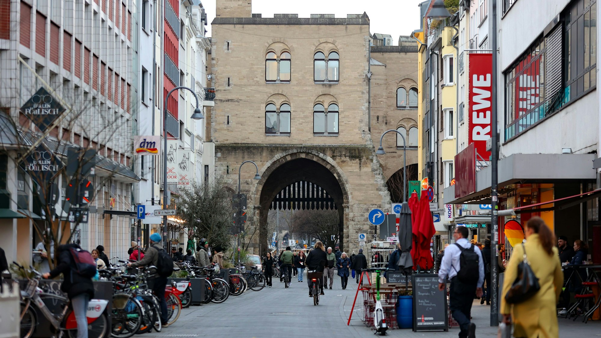 Menschen gehen zu Fuß oder fahren mit dem Fahrrad über den Eigelstein in Köln.