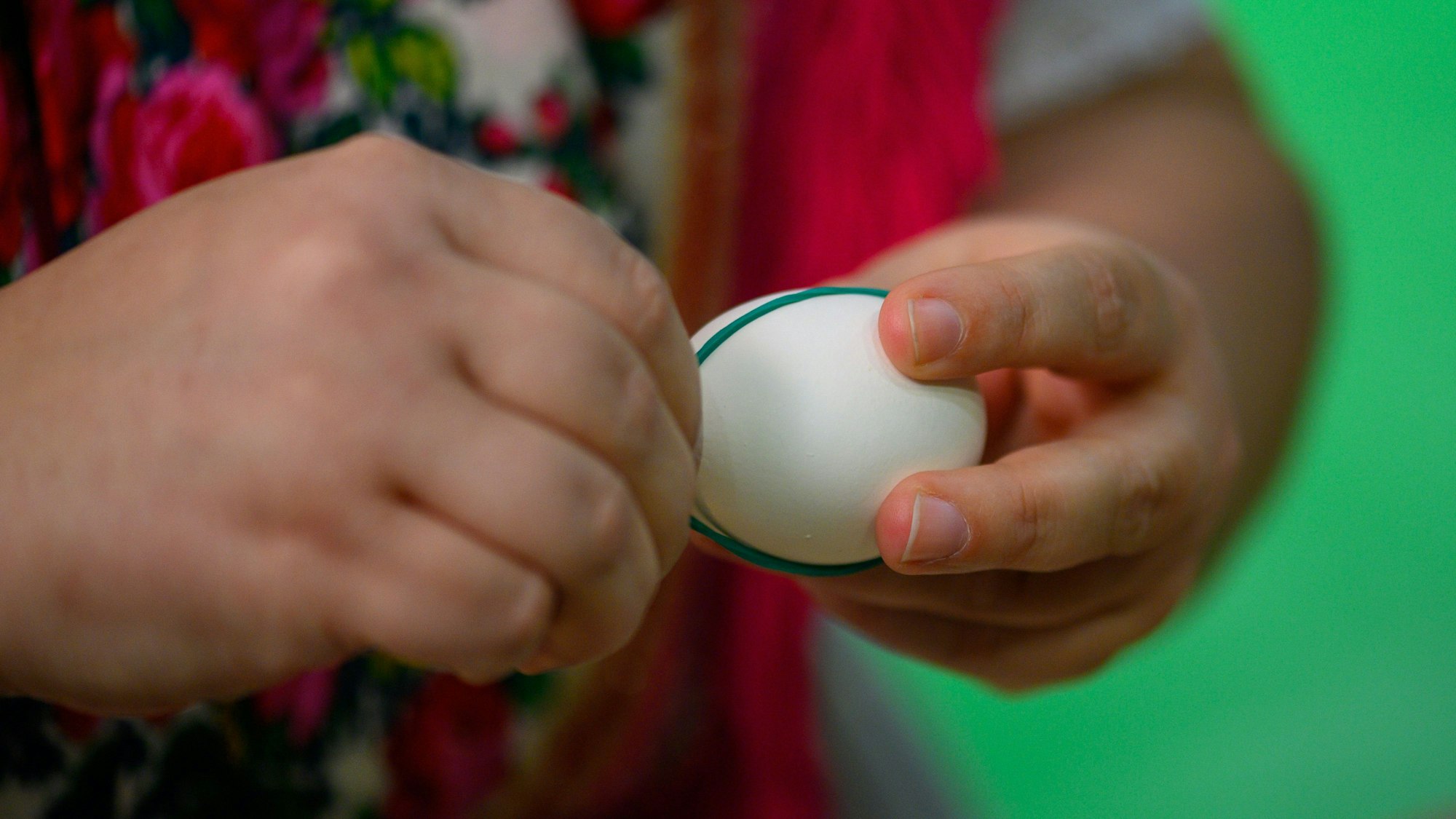 Eine Frau setzt Gummibänder auf ein weißes Ei