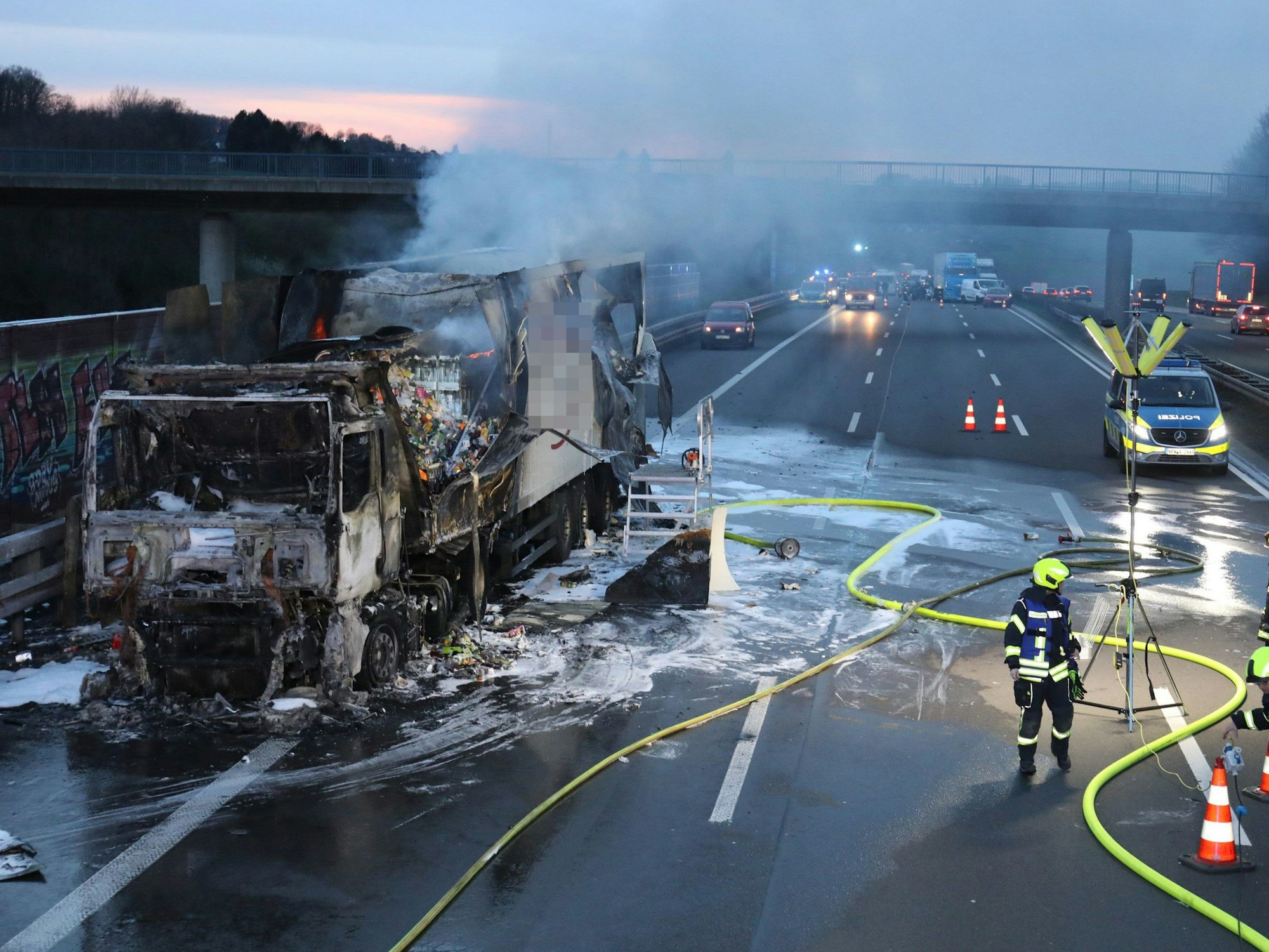 Einsatzkräfte der Feuerwehr löschen einen in Brand geratenen Lkw auf der Autobahn 3 bei Königswinter. Der brennende Laster mit Lebensmitteln an Bord hat am Donnerstagabend für Staus auf der A3 Richtung Frankfurt gesorgt.