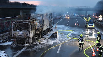 Einsatzkräfte der Feuerwehr löschen einen in Brand geratenen Lkw auf der Autobahn 3 bei Königswinter. Der brennende Laster mit Lebensmitteln an Bord hat am Donnerstagabend für Staus auf der A3 Richtung Frankfurt gesorgt.